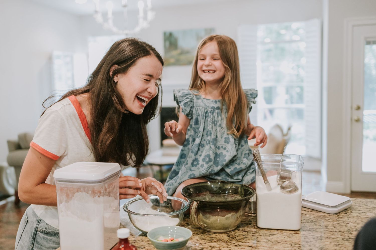 Group of people sitting around a kitchen counter baking and decorating Christmas cookies together.