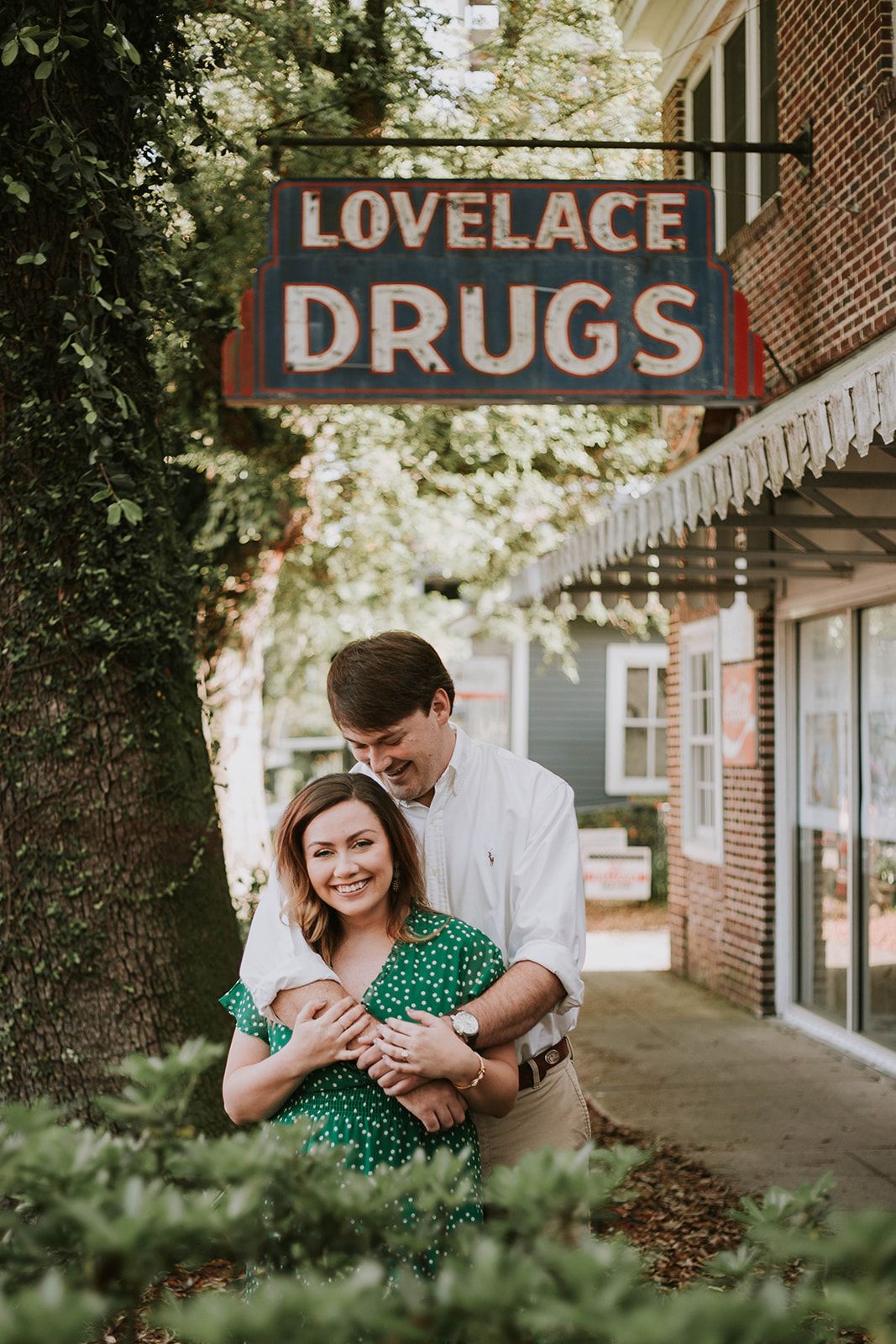 A couple embraces outside a vintage Lovelace Drugs storefront during a romantic photoshoot.