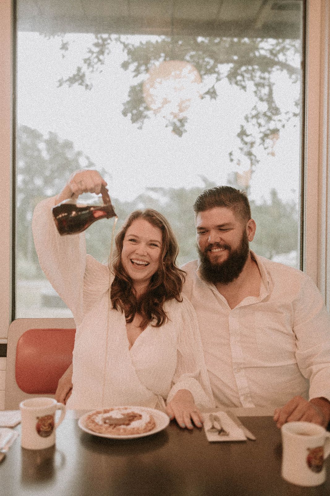 A couple laughing together while dining at a casual restaurant.