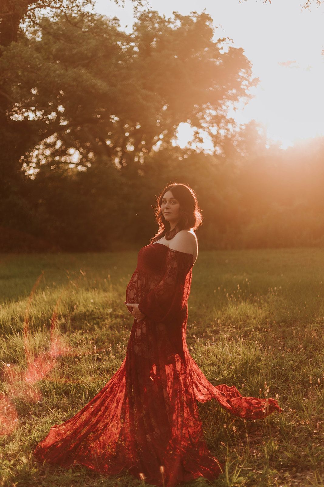 Figure in red dress twirls in sunlit field during golden hour.