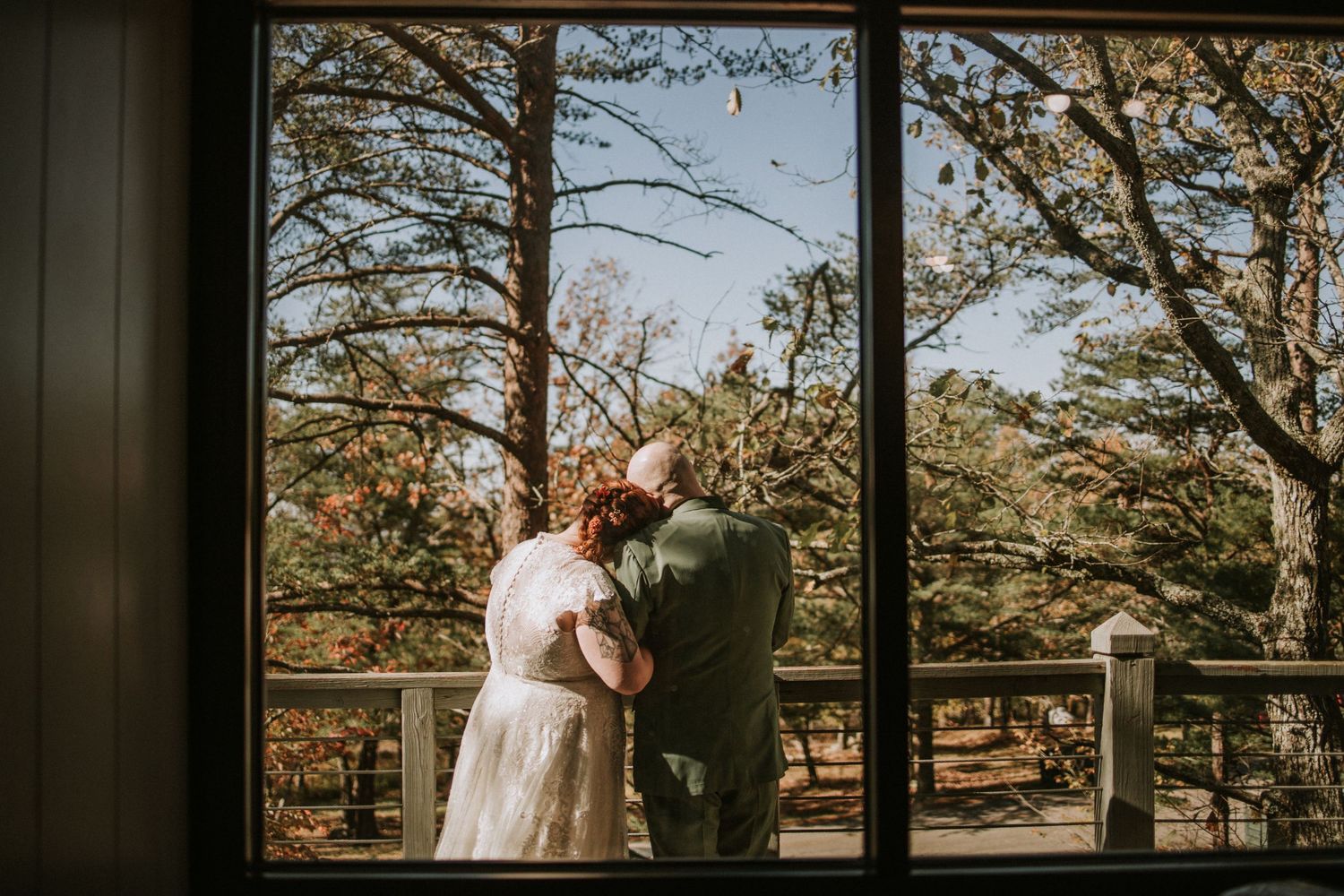 A romantic silhouette of a couple by a window overlooking an autumn forest scene.