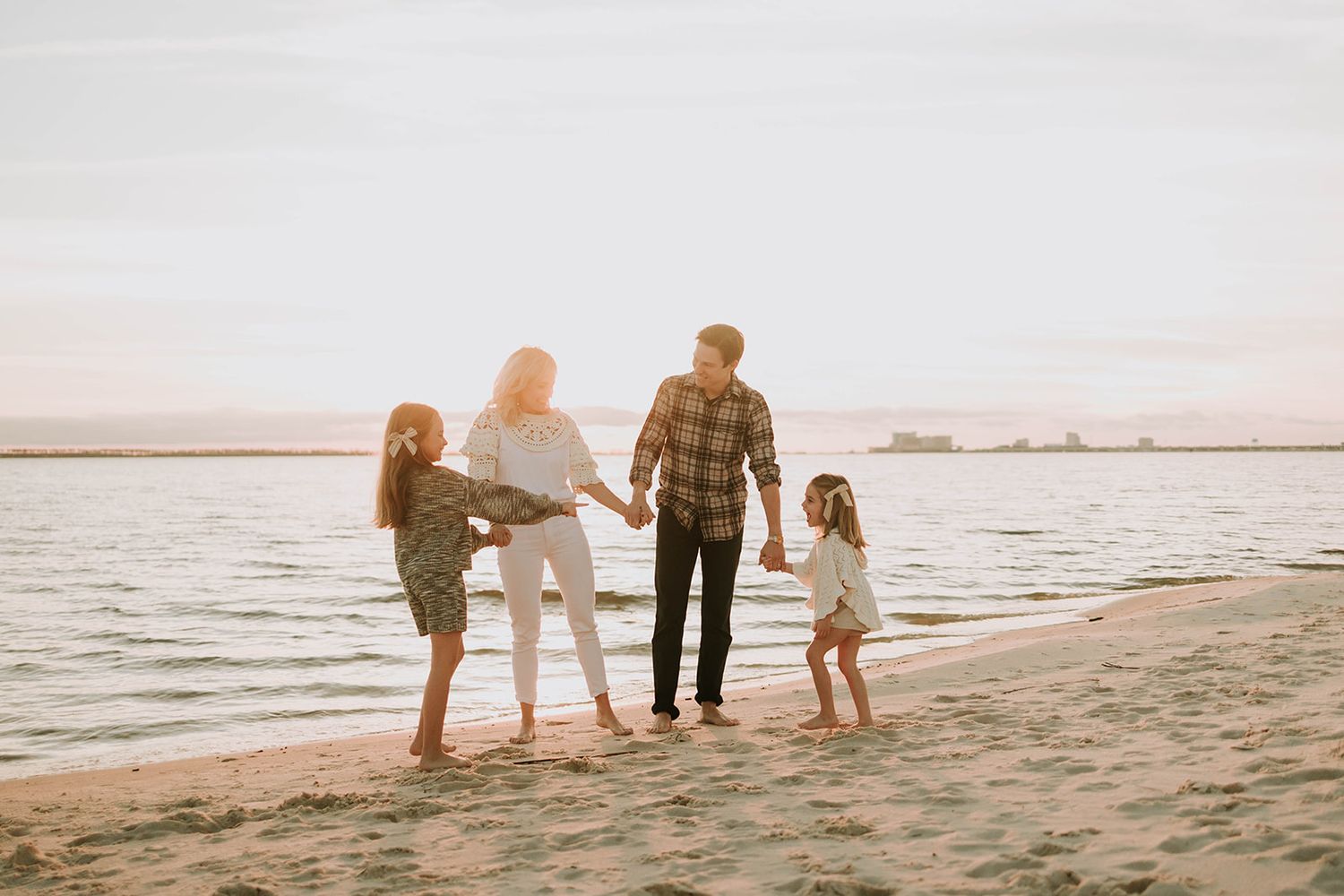 Silhouetted family walking together on beach during golden hour.