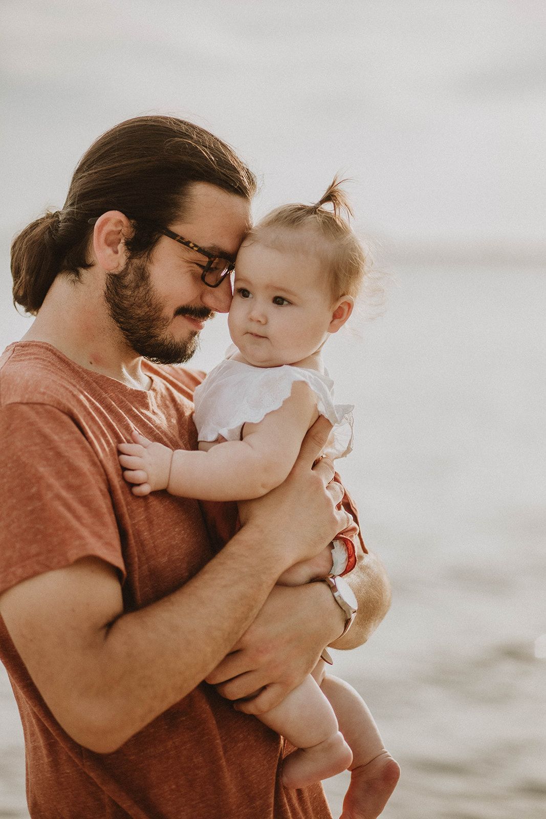Tender moment between parent and child against a soft, bright background.