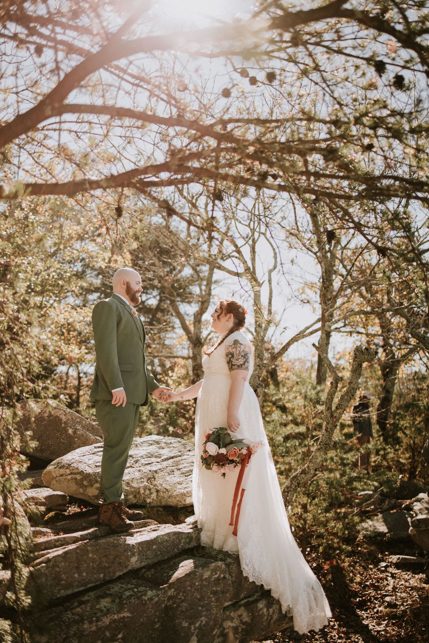 A couple stands together on rocky terrain during a romantic sunset wedding photoshoot in nature.