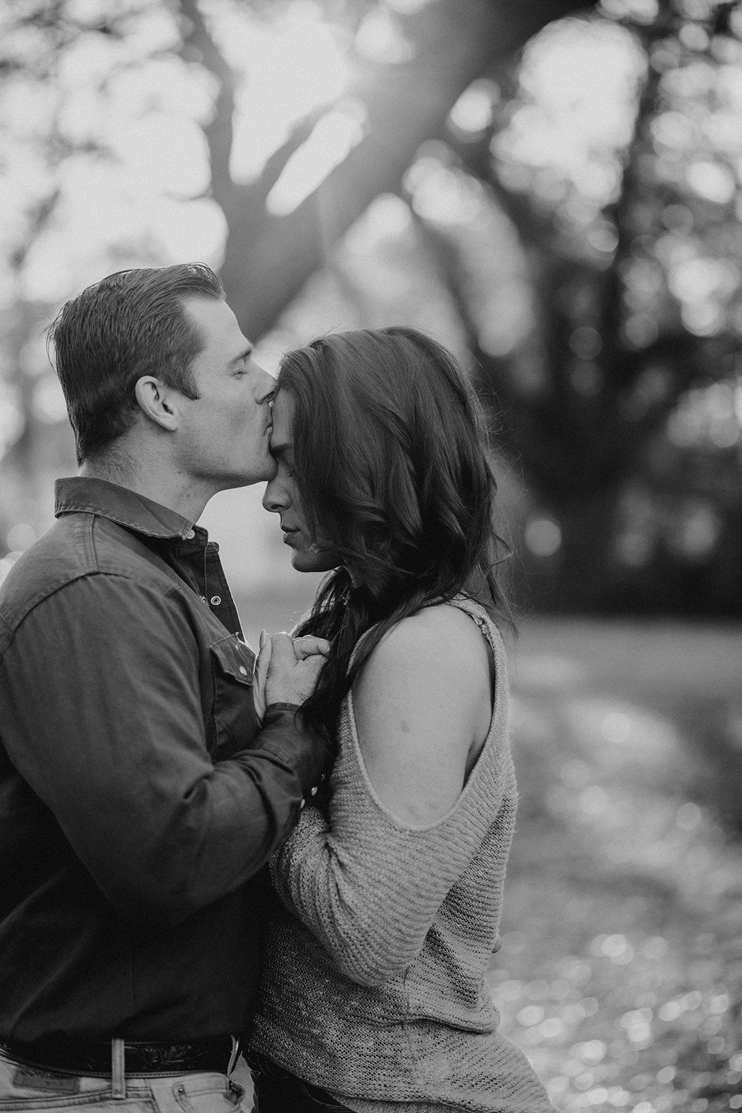 Intimate black and white portrait of couple sharing tender moment outdoors.