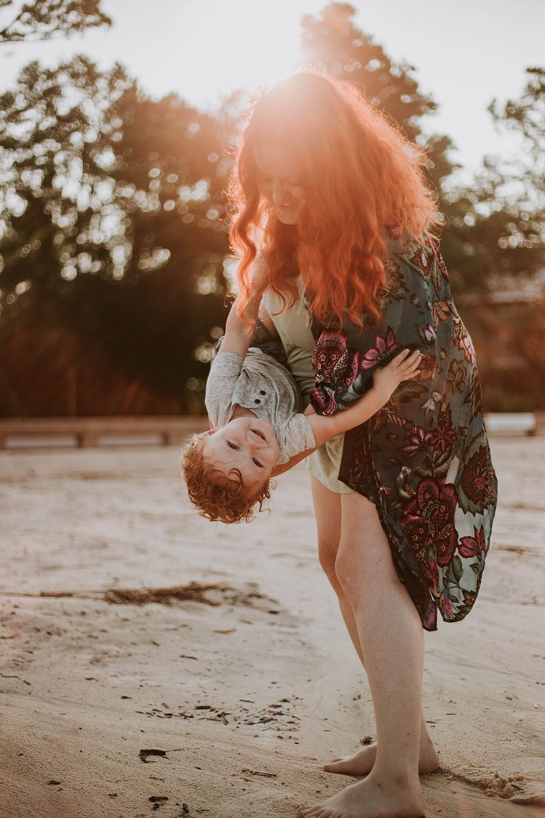 A sunset photoshoot on a beach featuring a floral dress and dramatic dip pose.