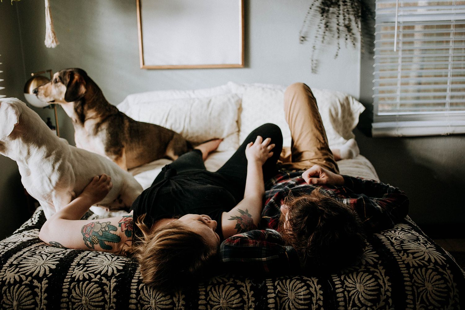 A playful couple enjoying a casual moment on a patterned couch with decorative throw pillows.
