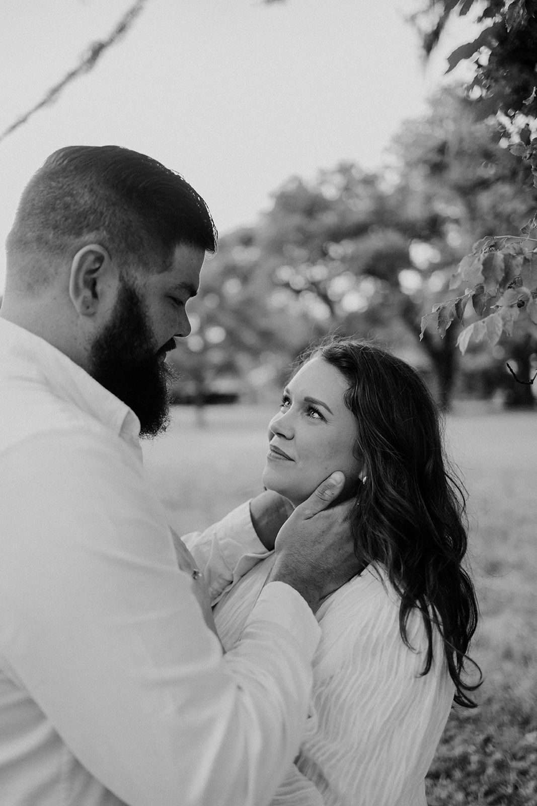 A tender outdoor portrait of a couple with the man gently touching her face.