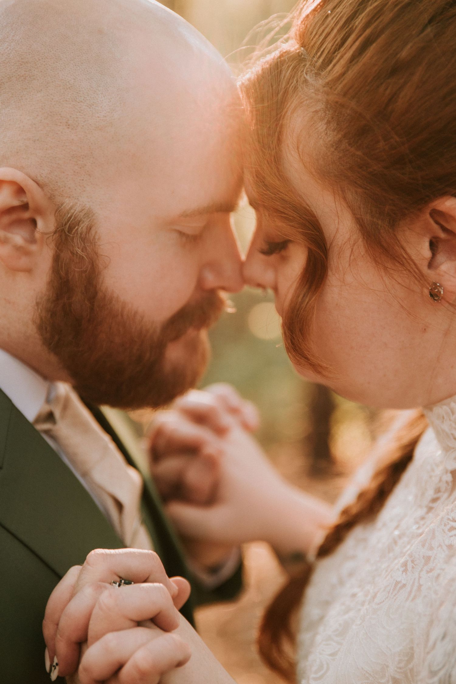 A tender intimate moment between newlyweds in warm sunlight as they embrace during their wedding day.