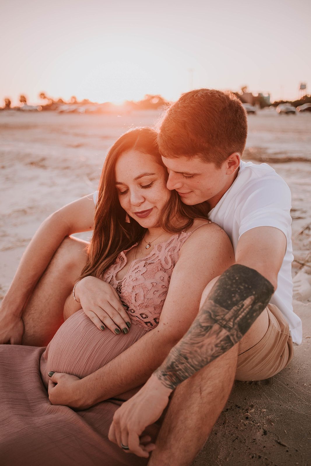 A couple shares an intimate moment on the beach during sunset.