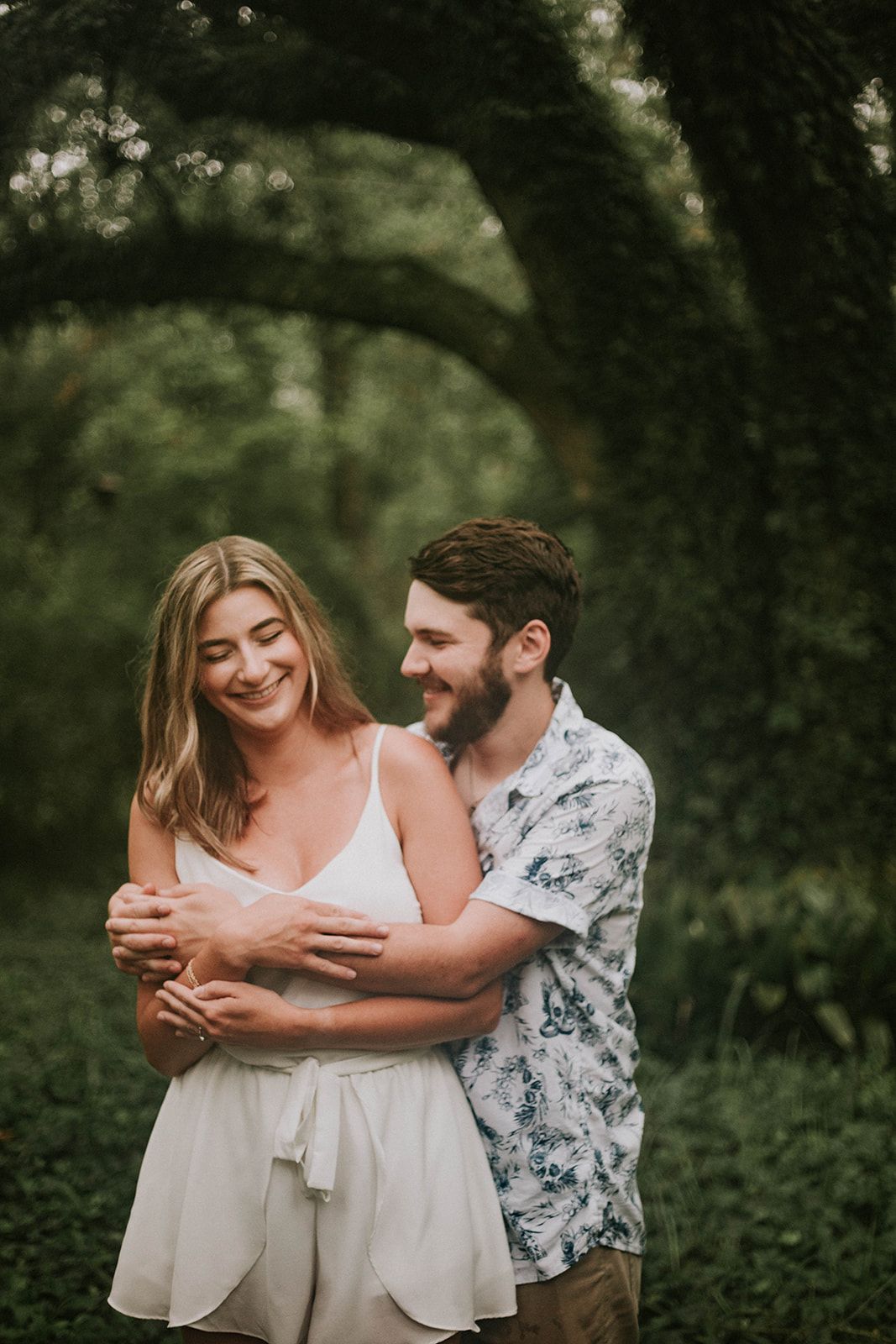 Couple sharing joyful embrace under lush green garden archway.