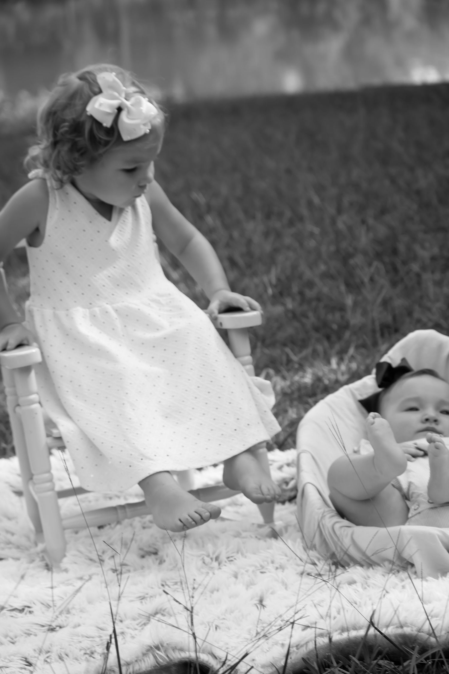 Sibling love captured in photo of young girl and baby sister in outdoor session