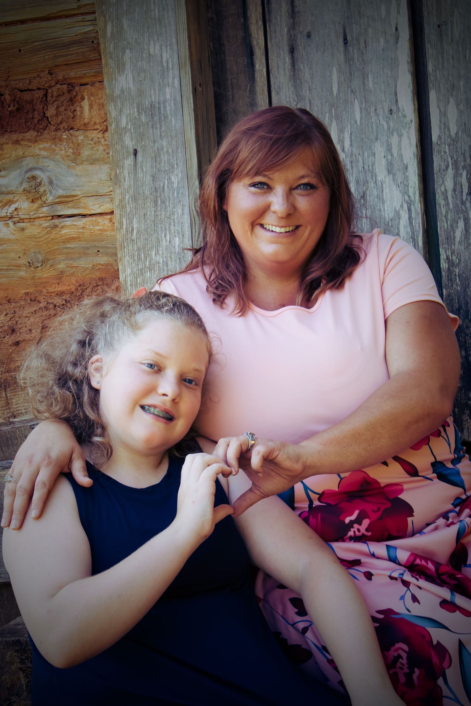 Mother and daughter making a heart symbol with there hands.