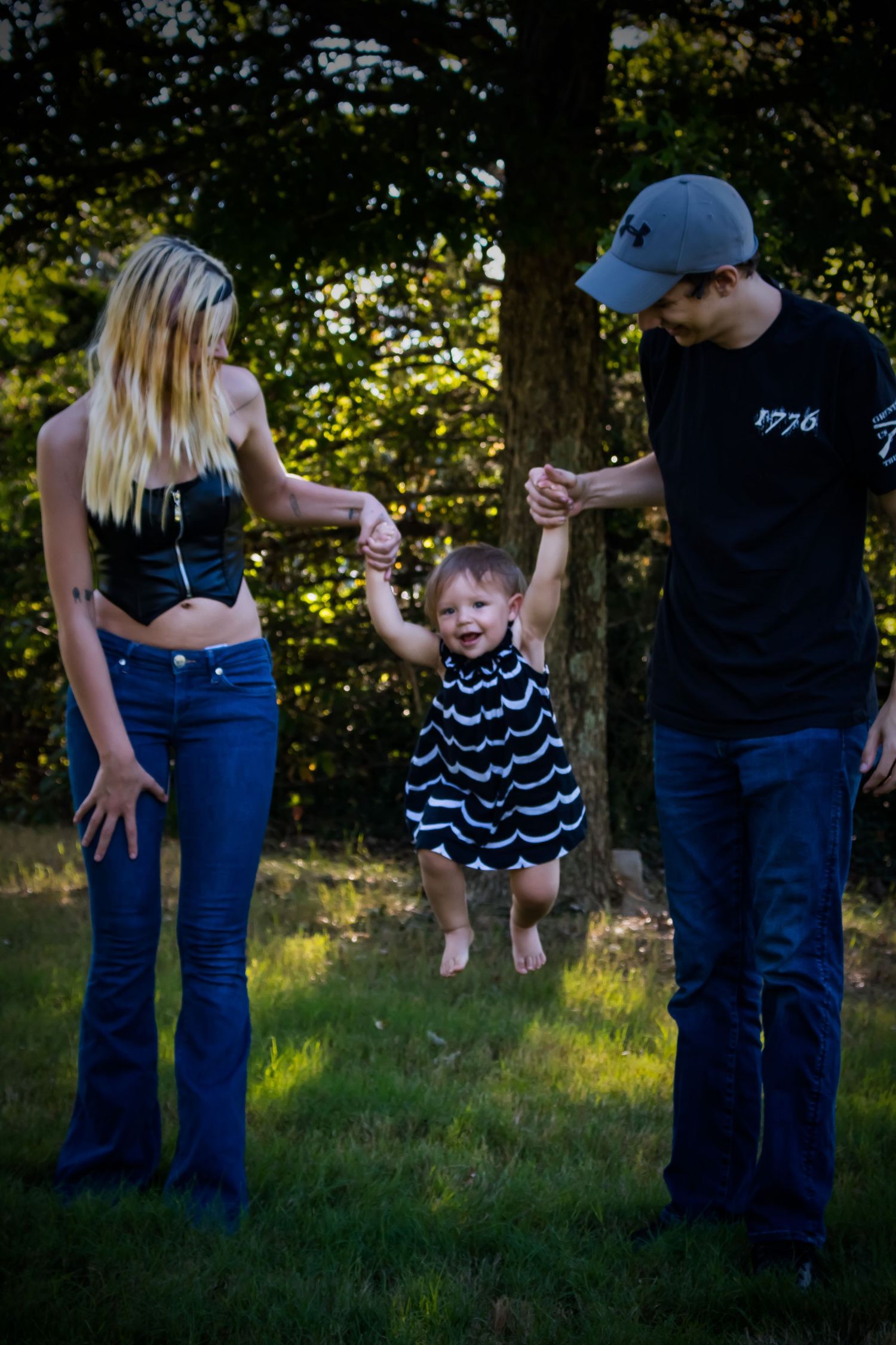 Mother and Father swinging baby girl in air by her arms.