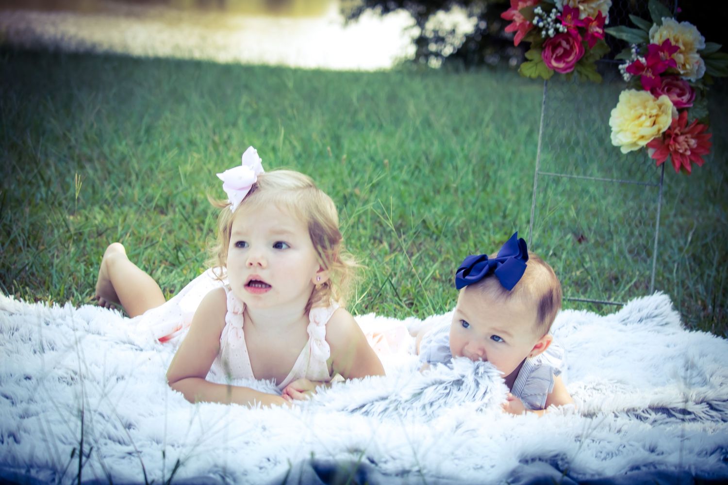 big sister and baby sister laying on blanket