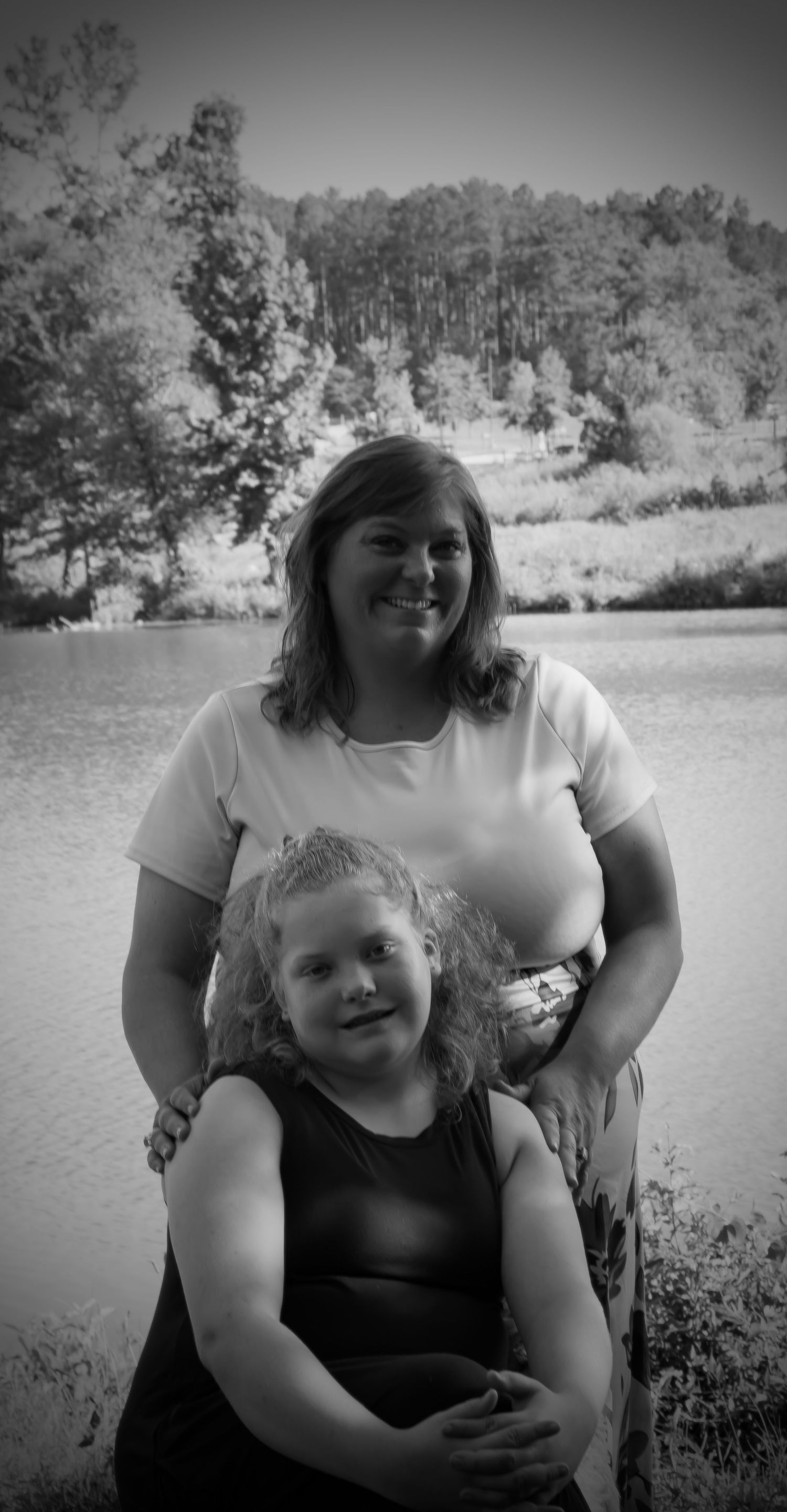 Tender portrait of mother and daughter with scenic lake backdrop