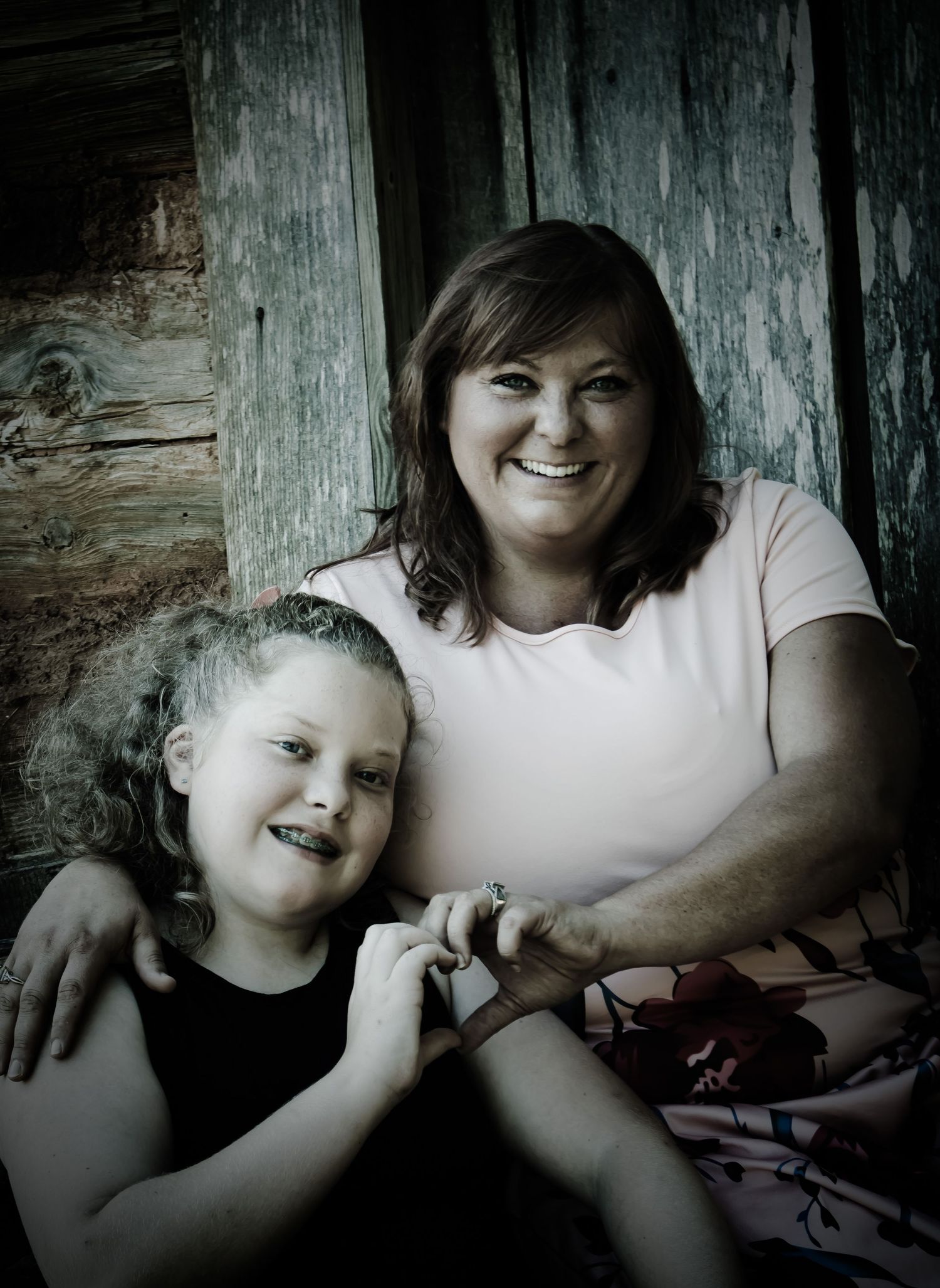 Tender moment of mother and daughter making heart with hands in rustic Georgia backdrop