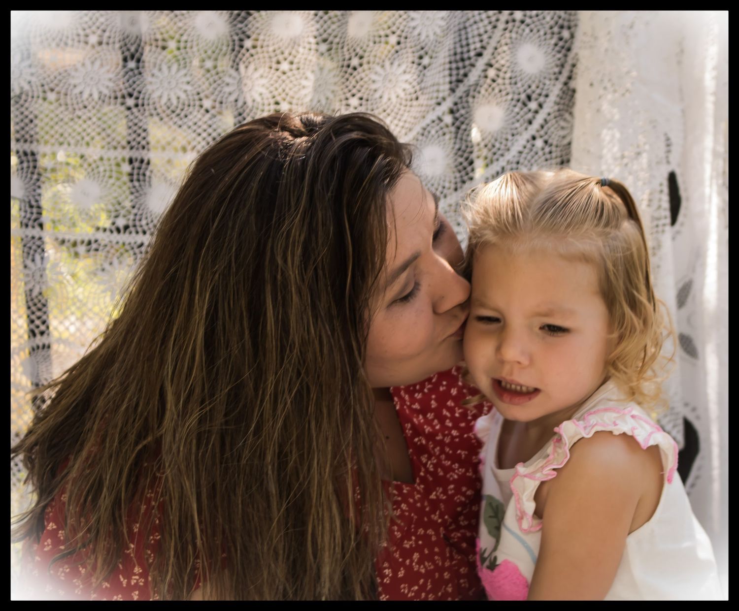 mom kissing her daughters cheek