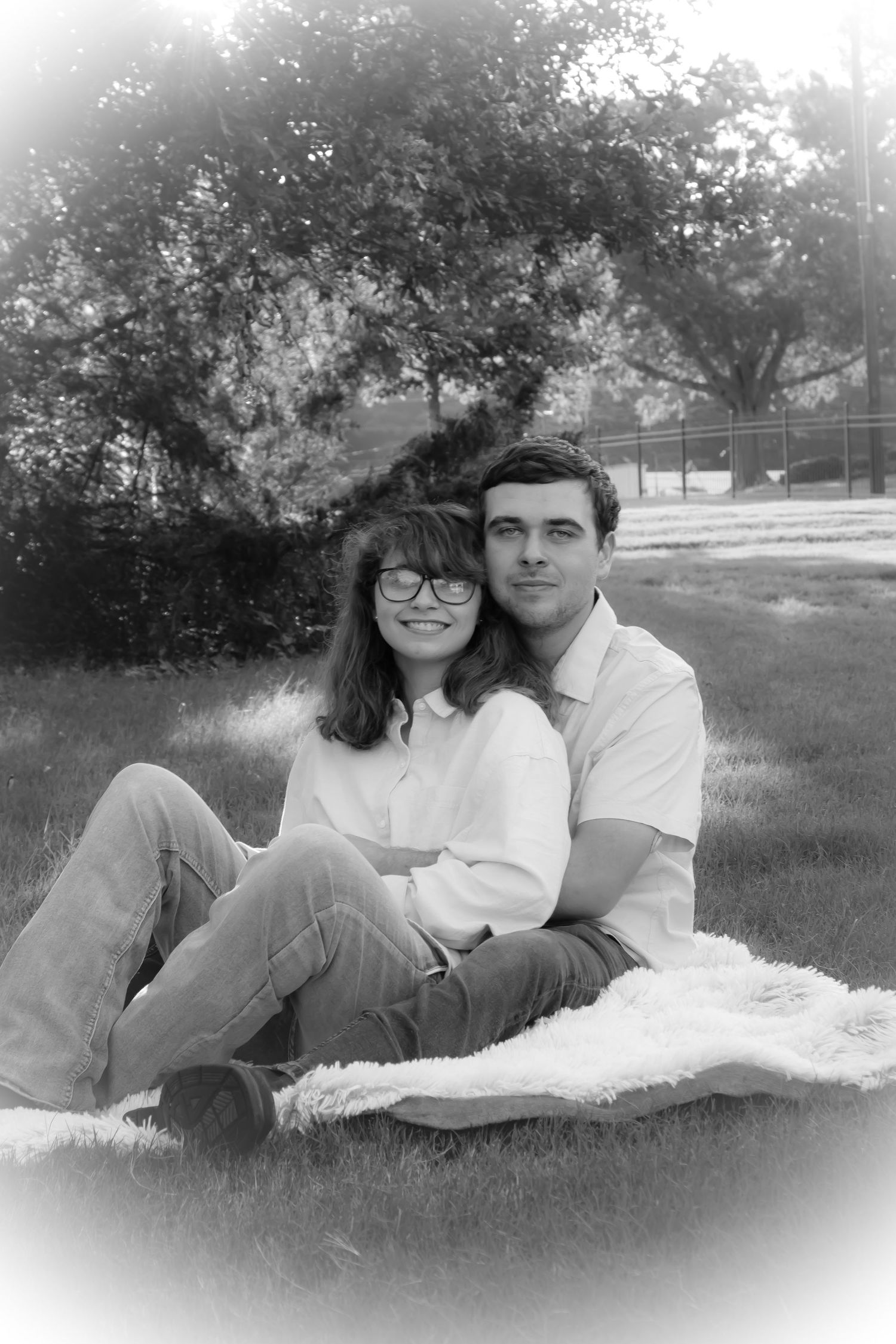Couple sitting together on grassy field during outdoor photo session