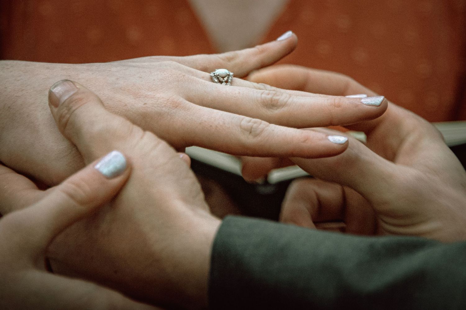 Close-up of groom placing a gold wedding ring on brides finger during intimate wedding ceremony.