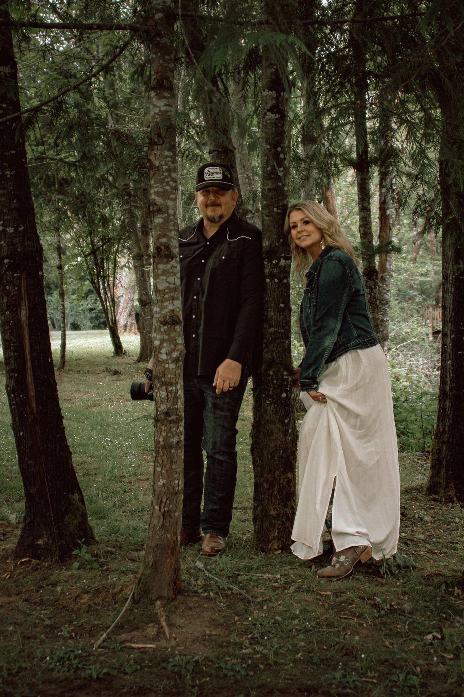 Couple posing among tall pine trees during an outdoor forest engagement photo session.