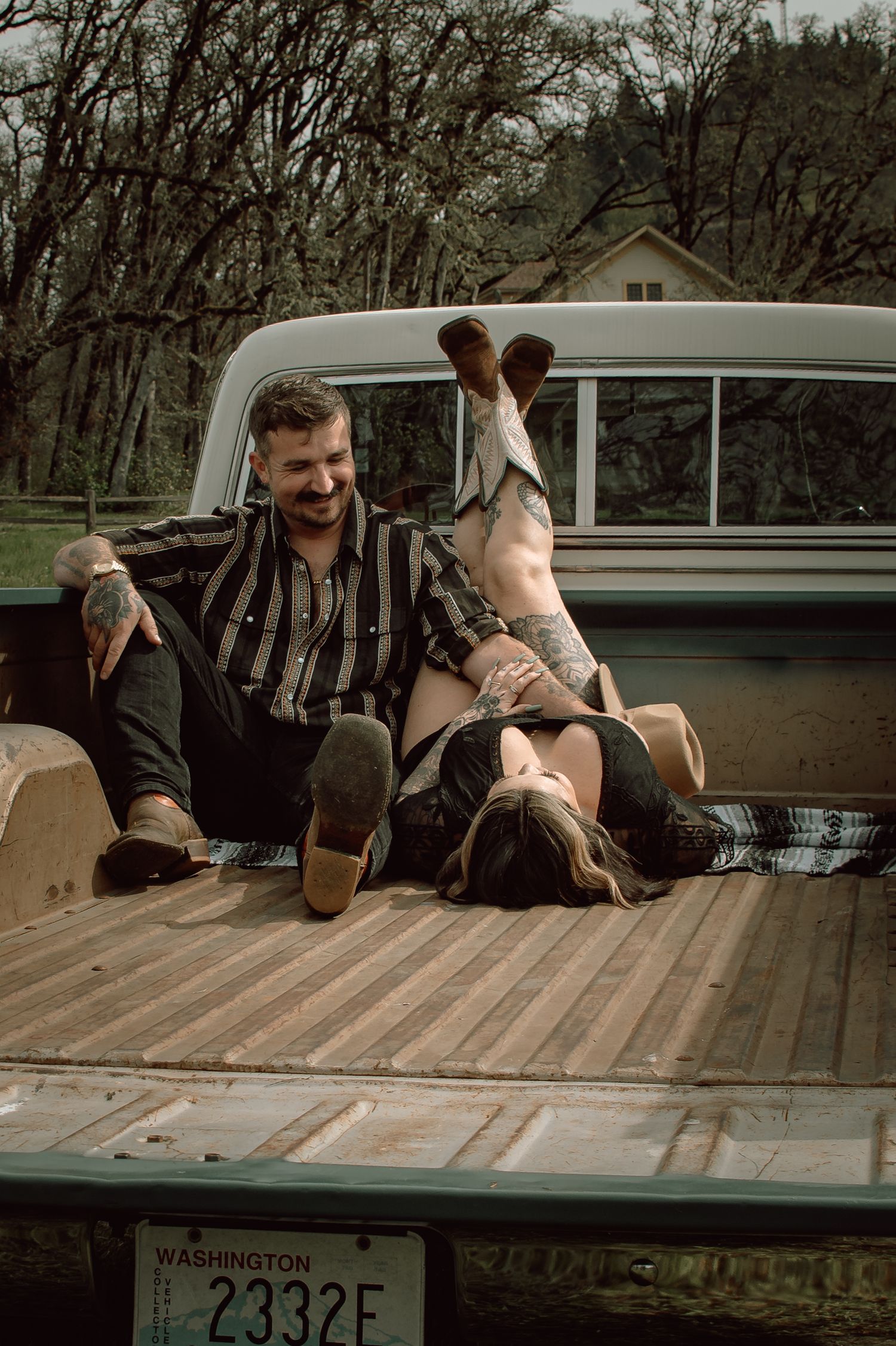 Laughing couple relaxing in the bed of a vintage Washington state pickup truck outdoors.