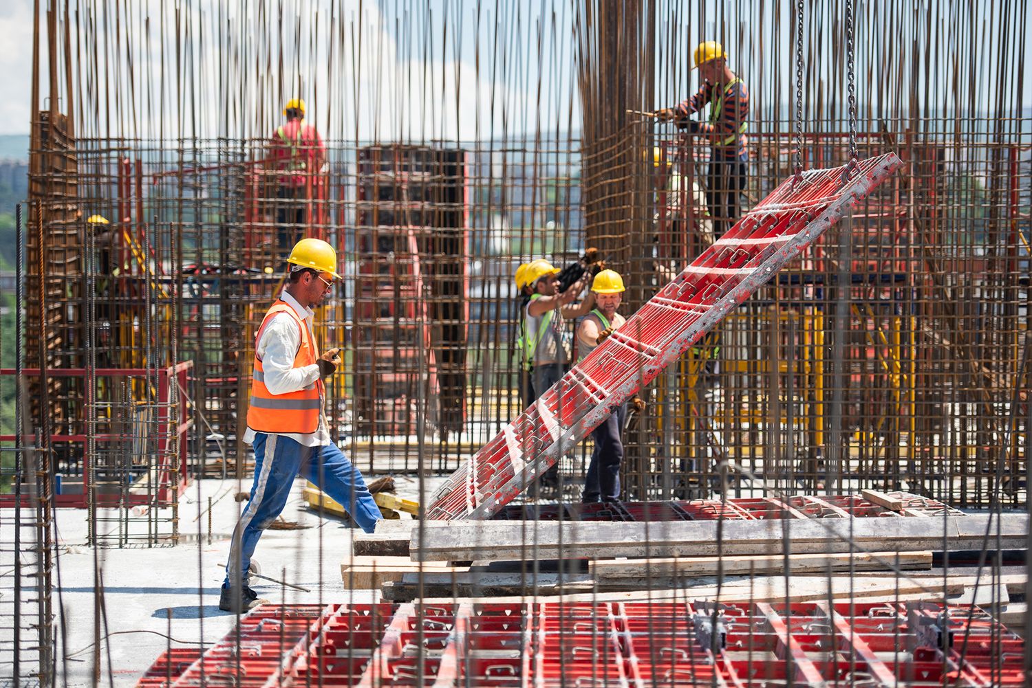 Worker guiding concrete pump hose on top of rebar mesh during foundation pouring.