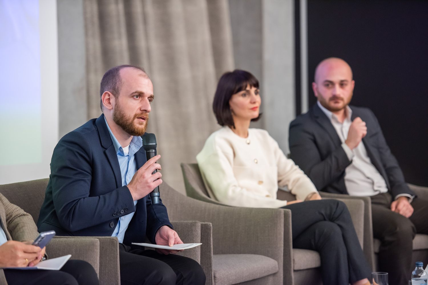 Close-up of a panel of three professionals engaged in discussion during a formal talk or forum.