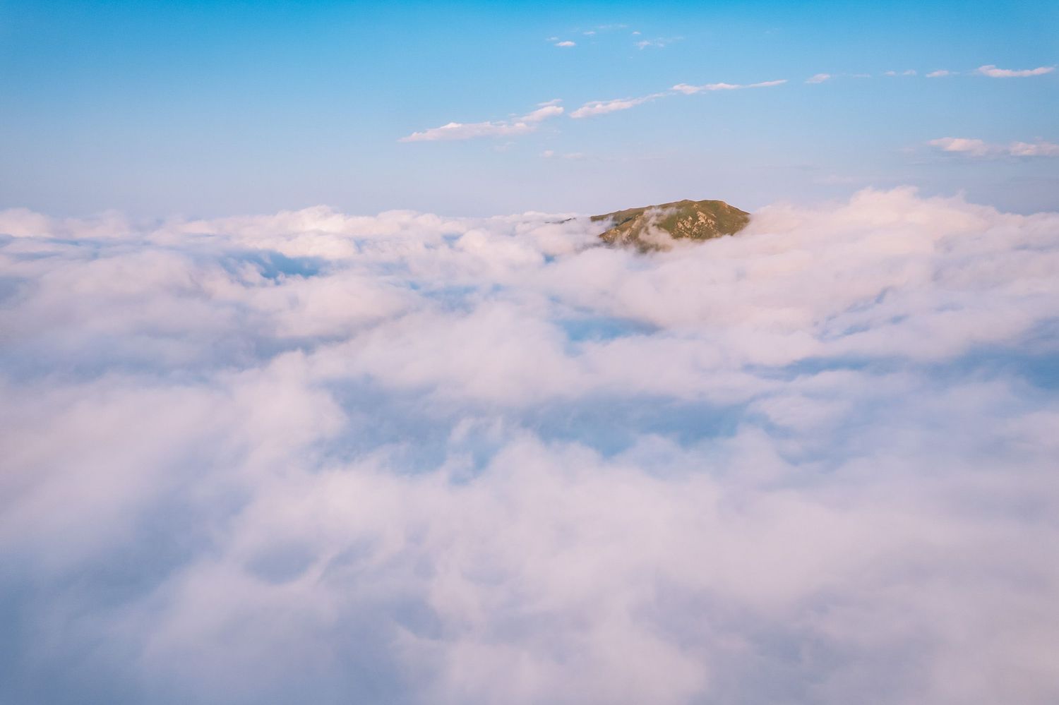 Majestic mountain peak emerging above the clouds during sunrise.