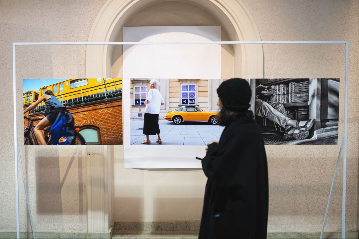 A person observing framed artwork at an indoor art gallery or museum exhibit.