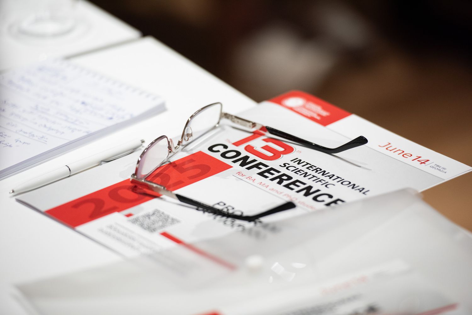 Close-up of documents, brochures, and branded materials spread on a desk, focused on marketing or event collateral.
