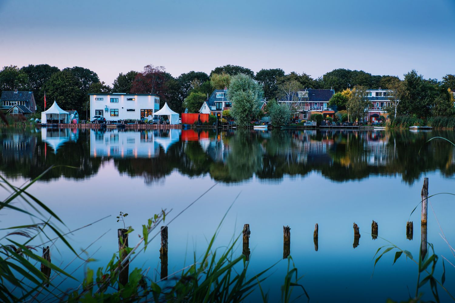 Quiet lakeside town reflected perfectly in still water — peaceful small-town setting at dusk.