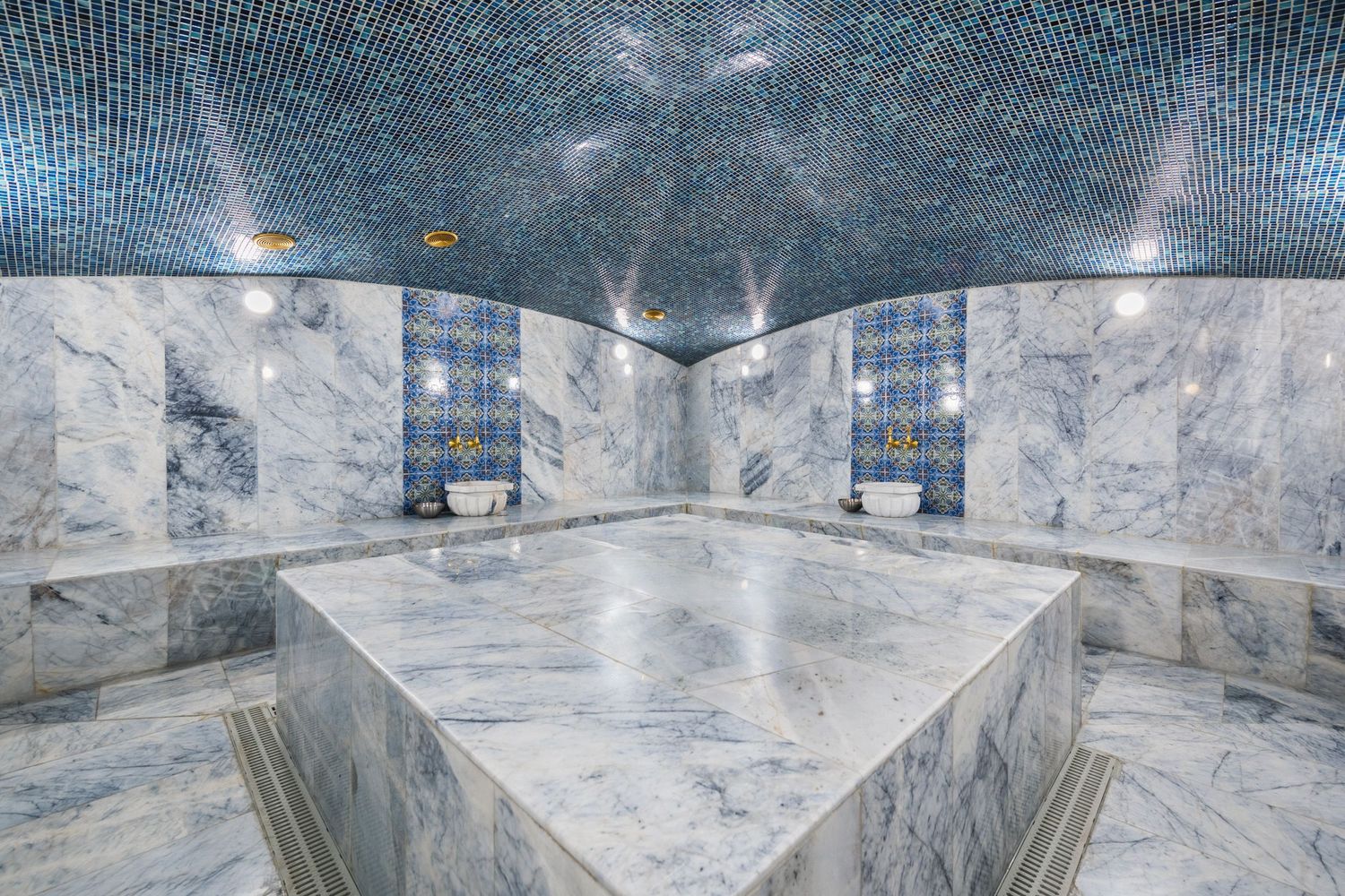 Luxurious hammam or spa interior featuring marble walls, symmetrical seating, and ambient lighting.