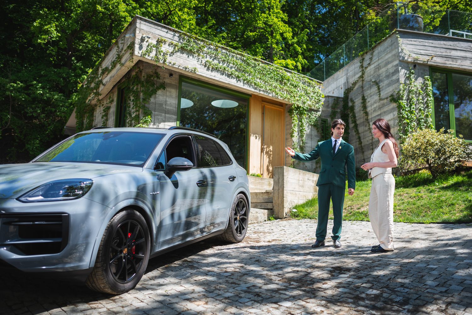 Two people standing beside a luxury SUV parked in front of a house — business or lifestyle context.