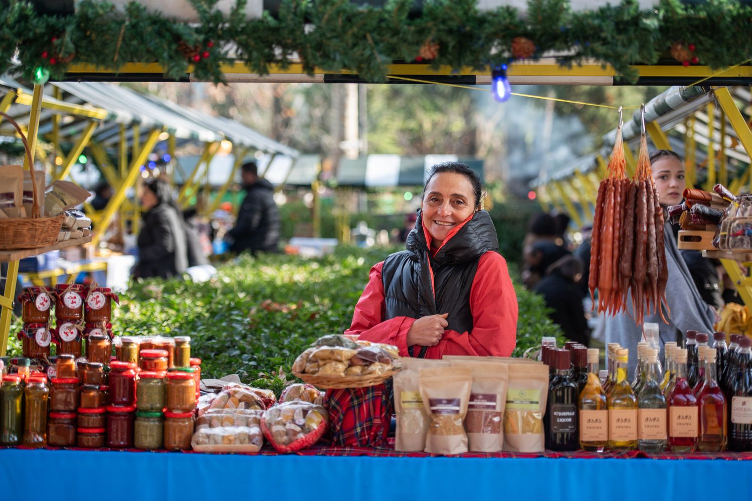 Local vendor selling homemade preserves and crafts at an outdoor farmers market.