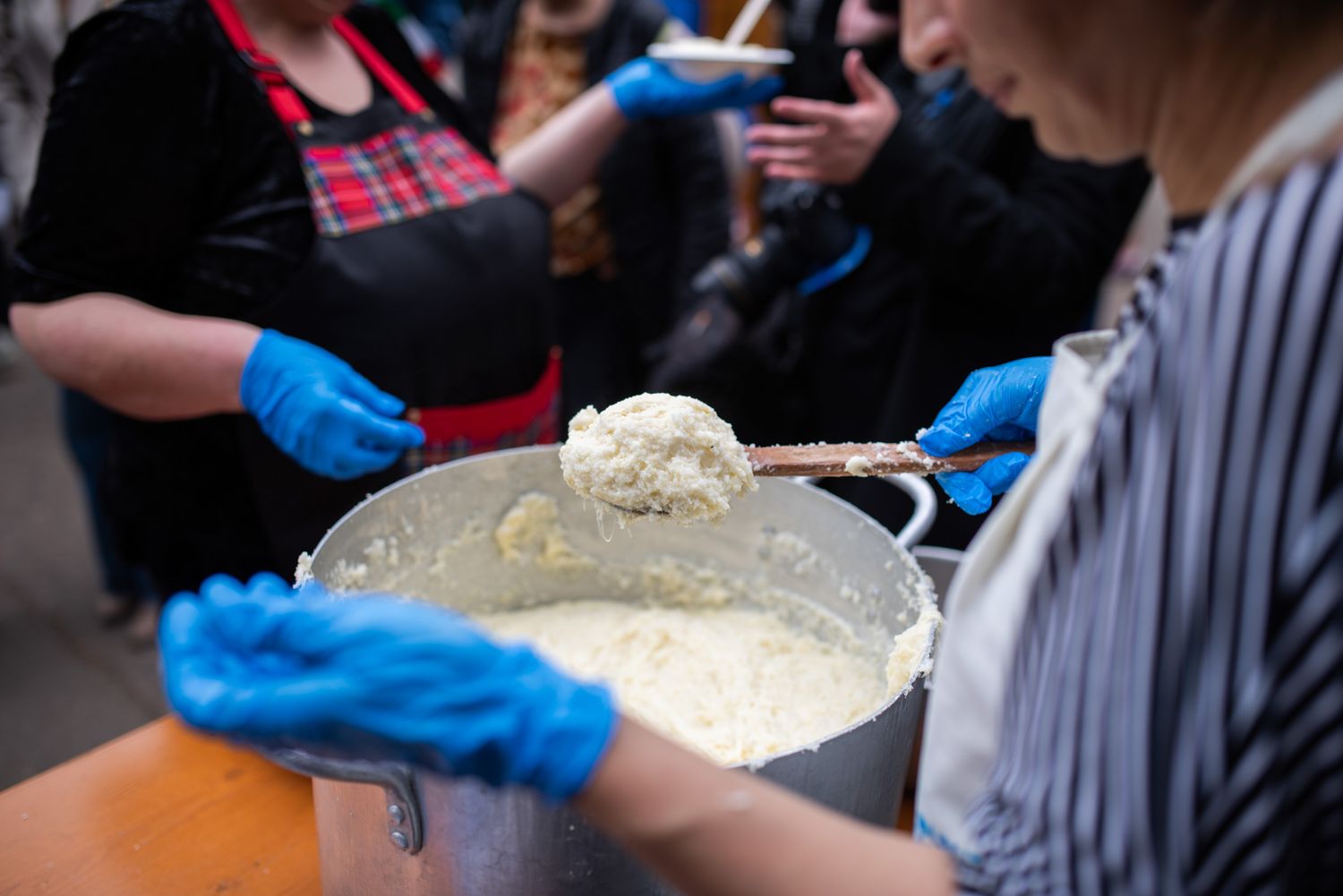 Close-up of a person crafting traditional cheese by hand at a food demonstration.