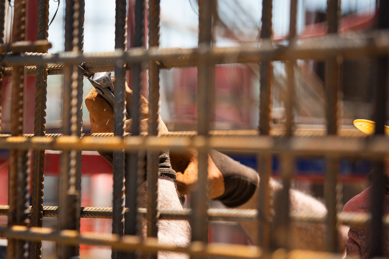 Detailed view of steel rebar grid with worker partially visible in the background.