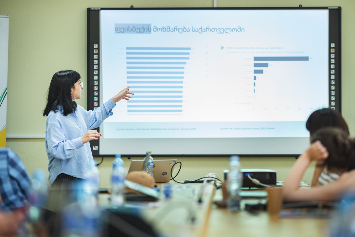 Female instructor explaining data on a projected screen during an educational workshop.