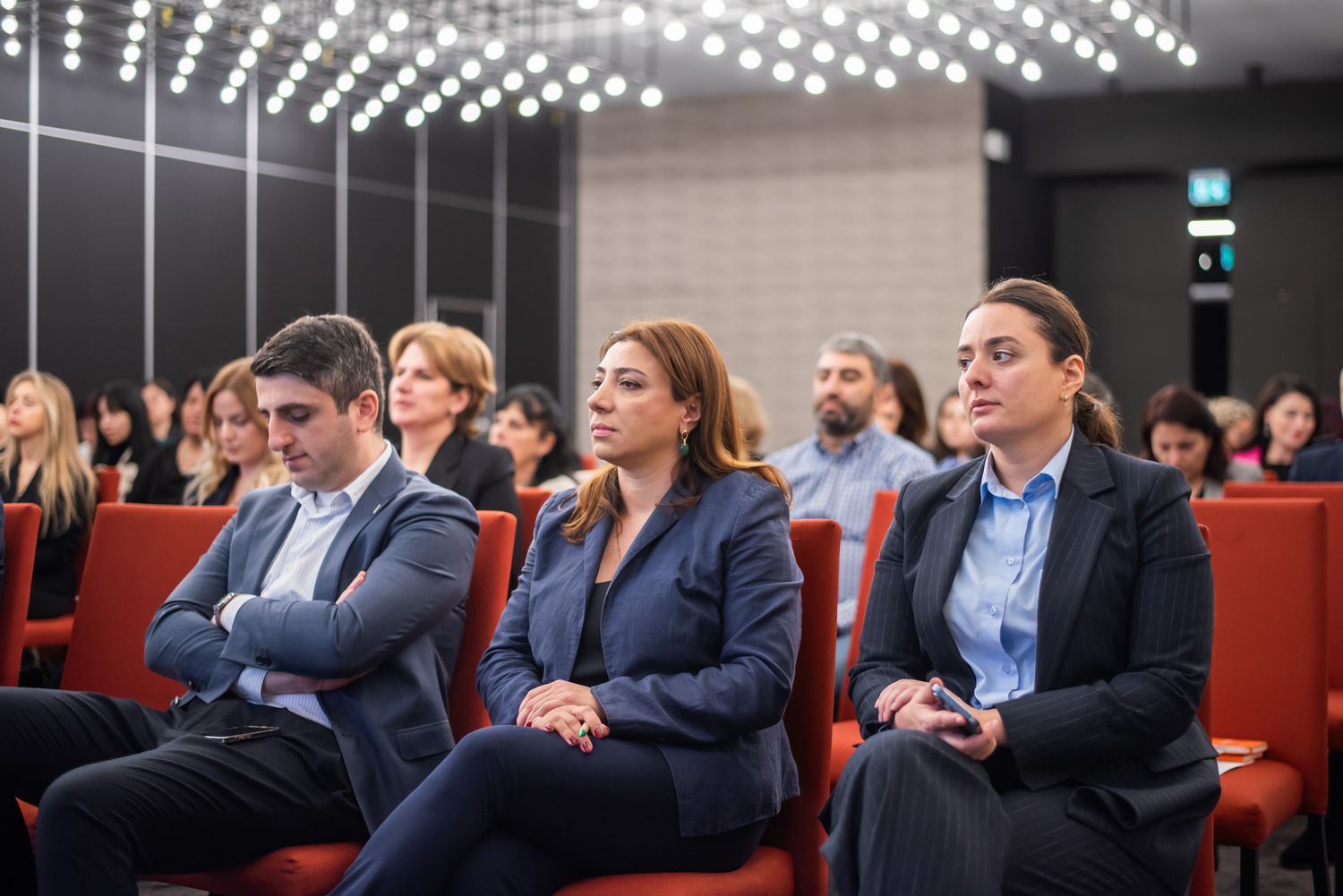 Audience seated in rows at a business conference, attentively listening to a speaker or presentation.