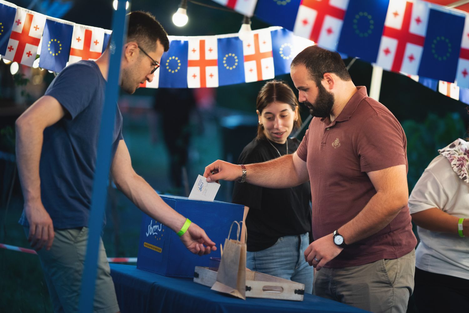 People participating in a cooking workshop or culinary demonstration with various flags overhead.