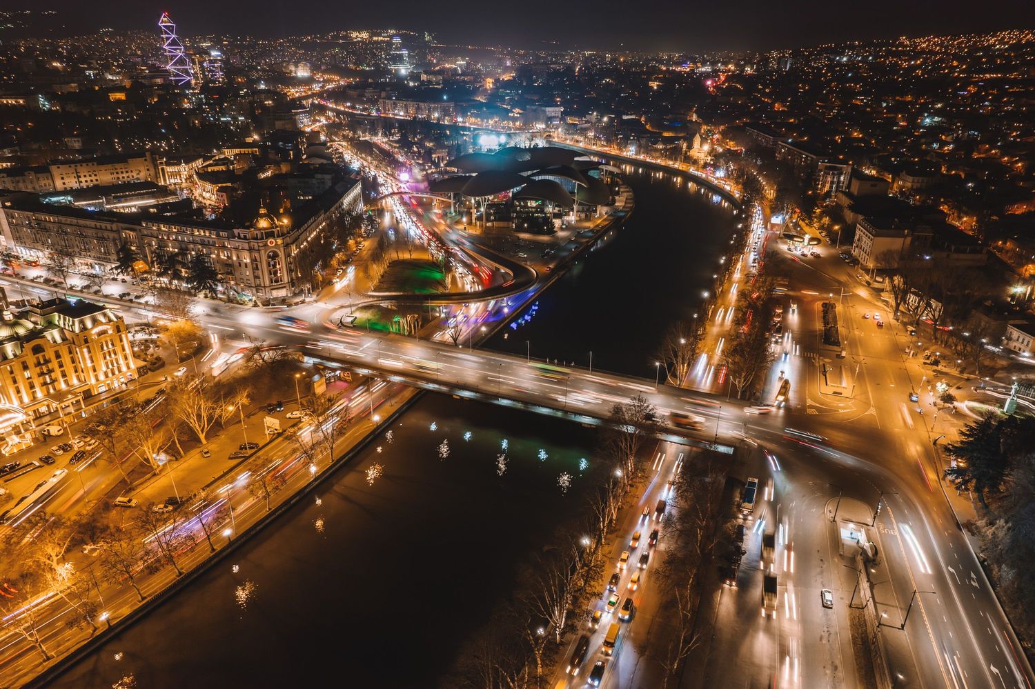 Night aerial view of a brightly lit city intersection — long exposure cityscape photography.