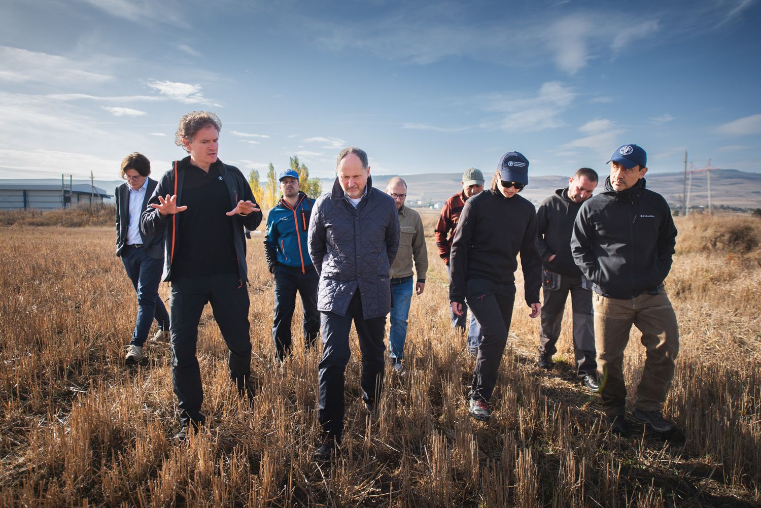 Group of men walking through a harvested wheat field in rural countryside.