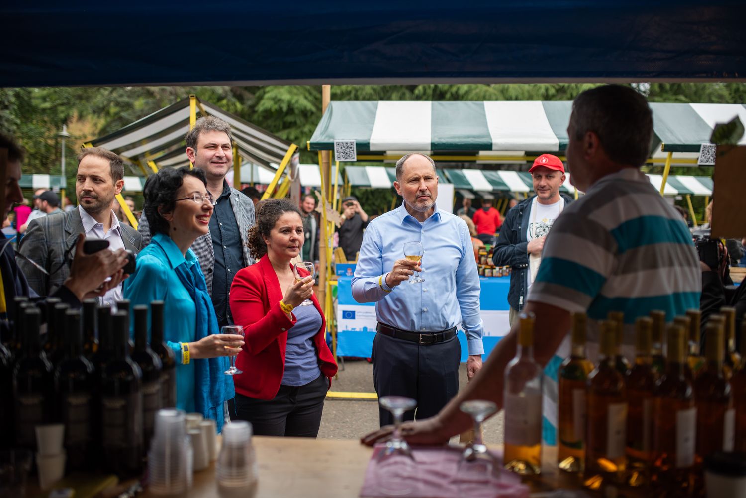 A group of visitors sampling local beverages at an open-air tasting event.