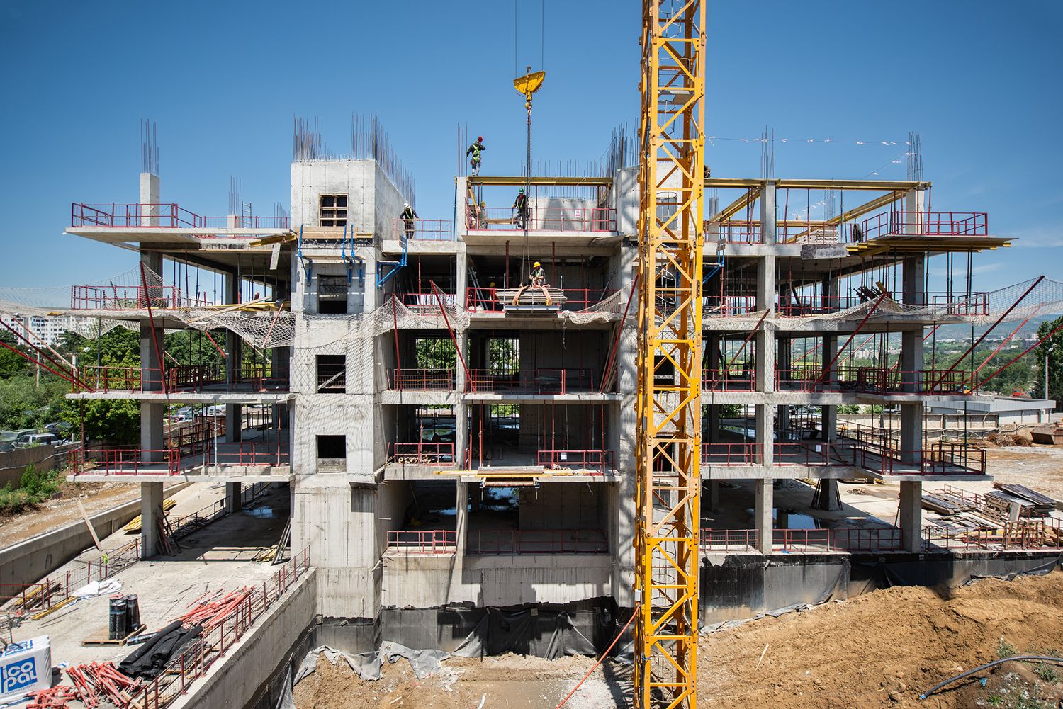 Partially constructed multi-story building with scaffolding and tower crane in a clear sky.