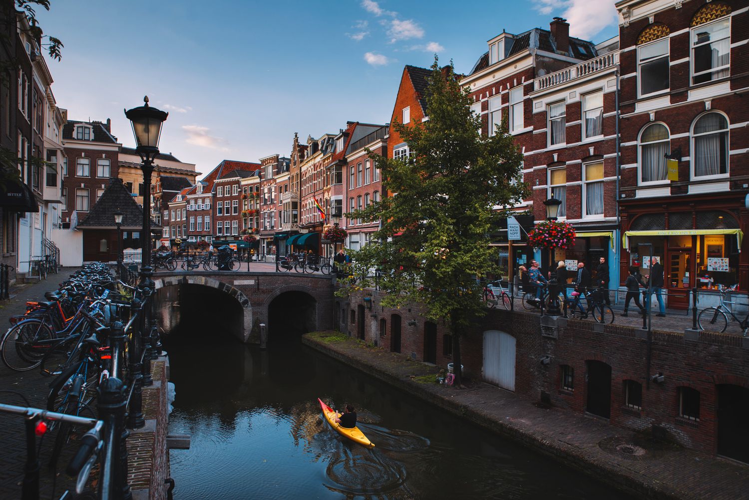 Busy canal street in Utrecht with people walking beside the water — urban charm and reflections.