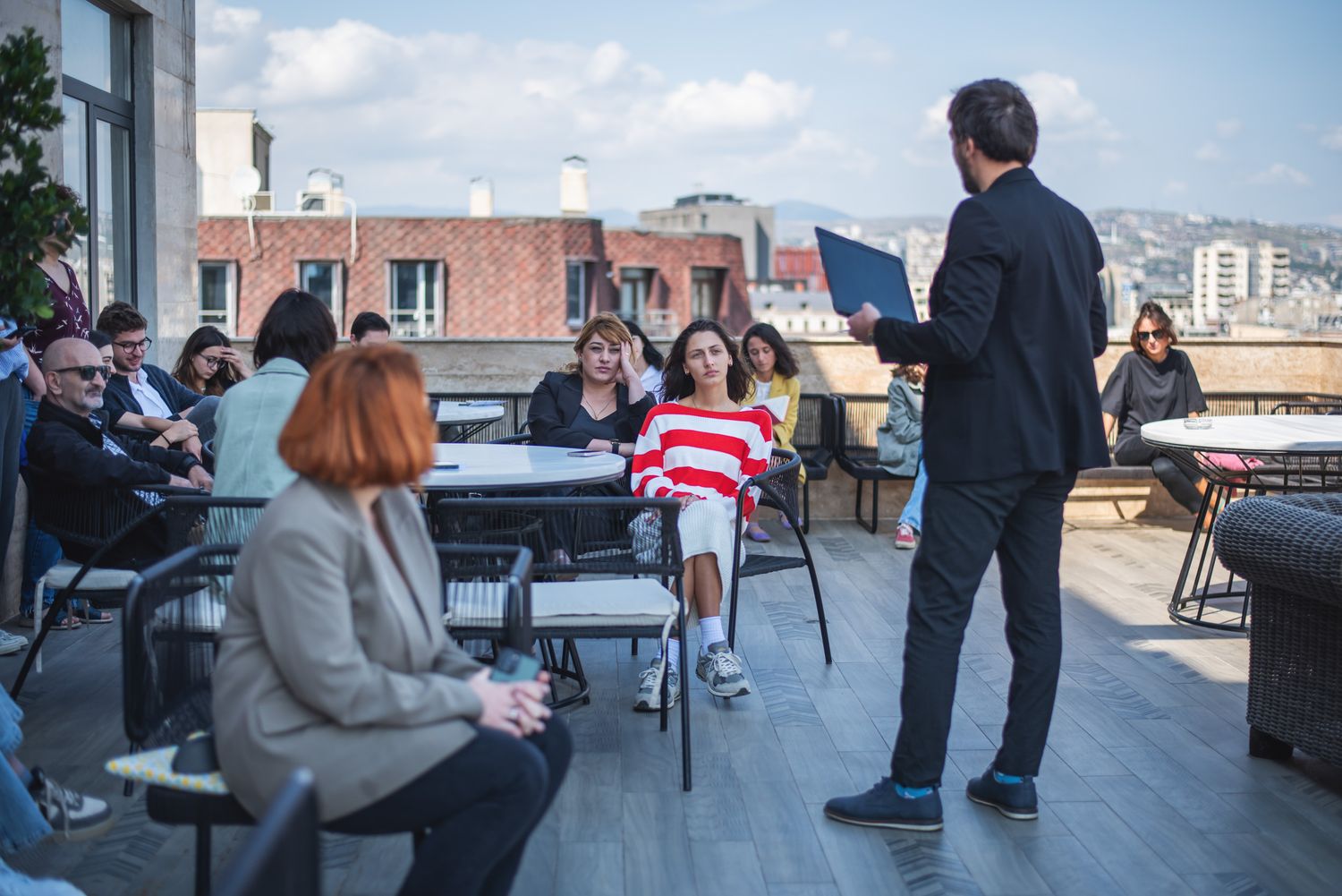Open-air group discussion on a rooftop terrace with a cityscape view.