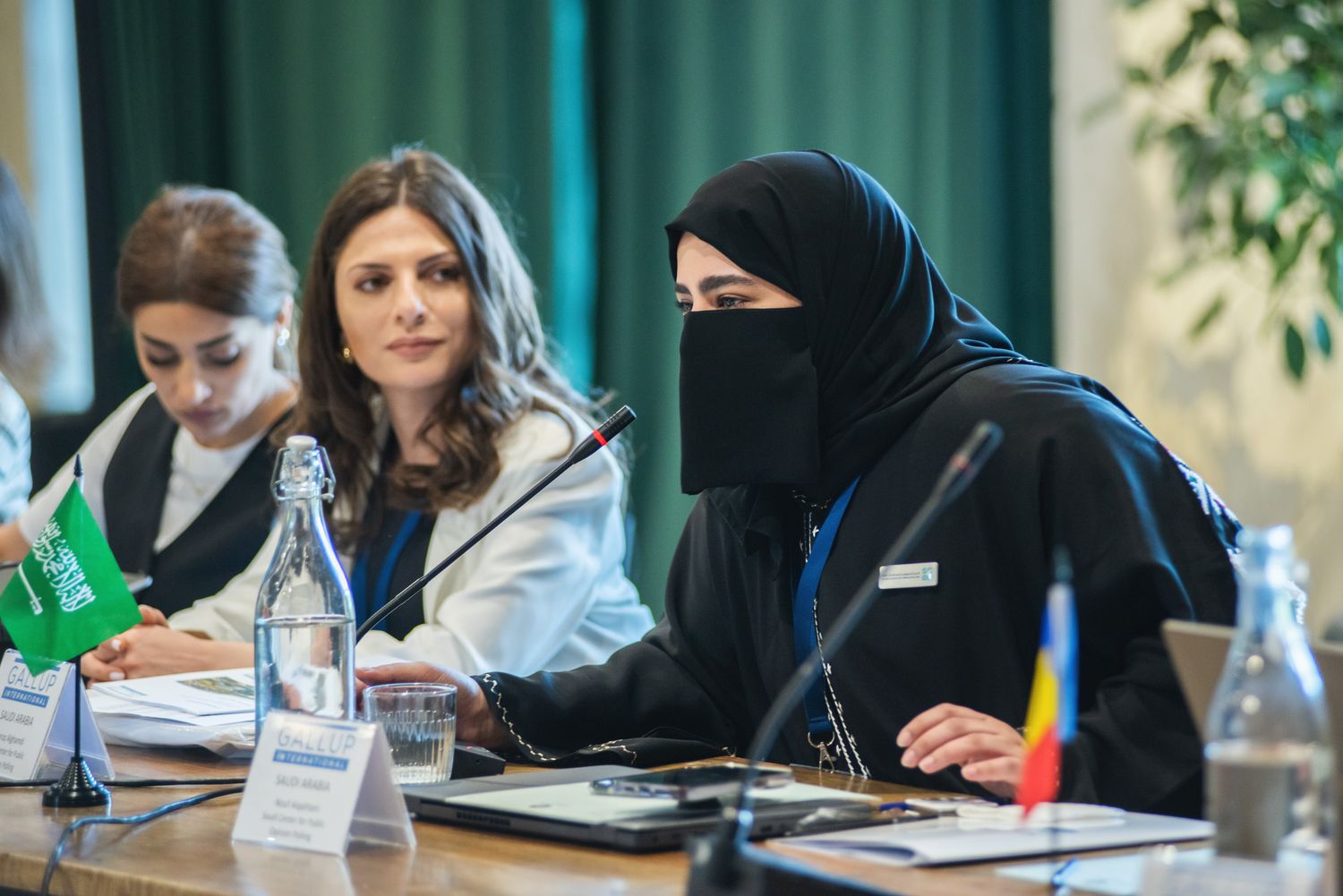 Two women in a discussion or Q&A session at a table, with conference materials and event branding visible.