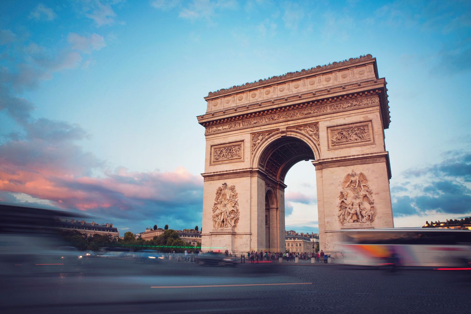 Arc de Triomphe at sunrise with soft pastel skies — historical monument in Paris, France.