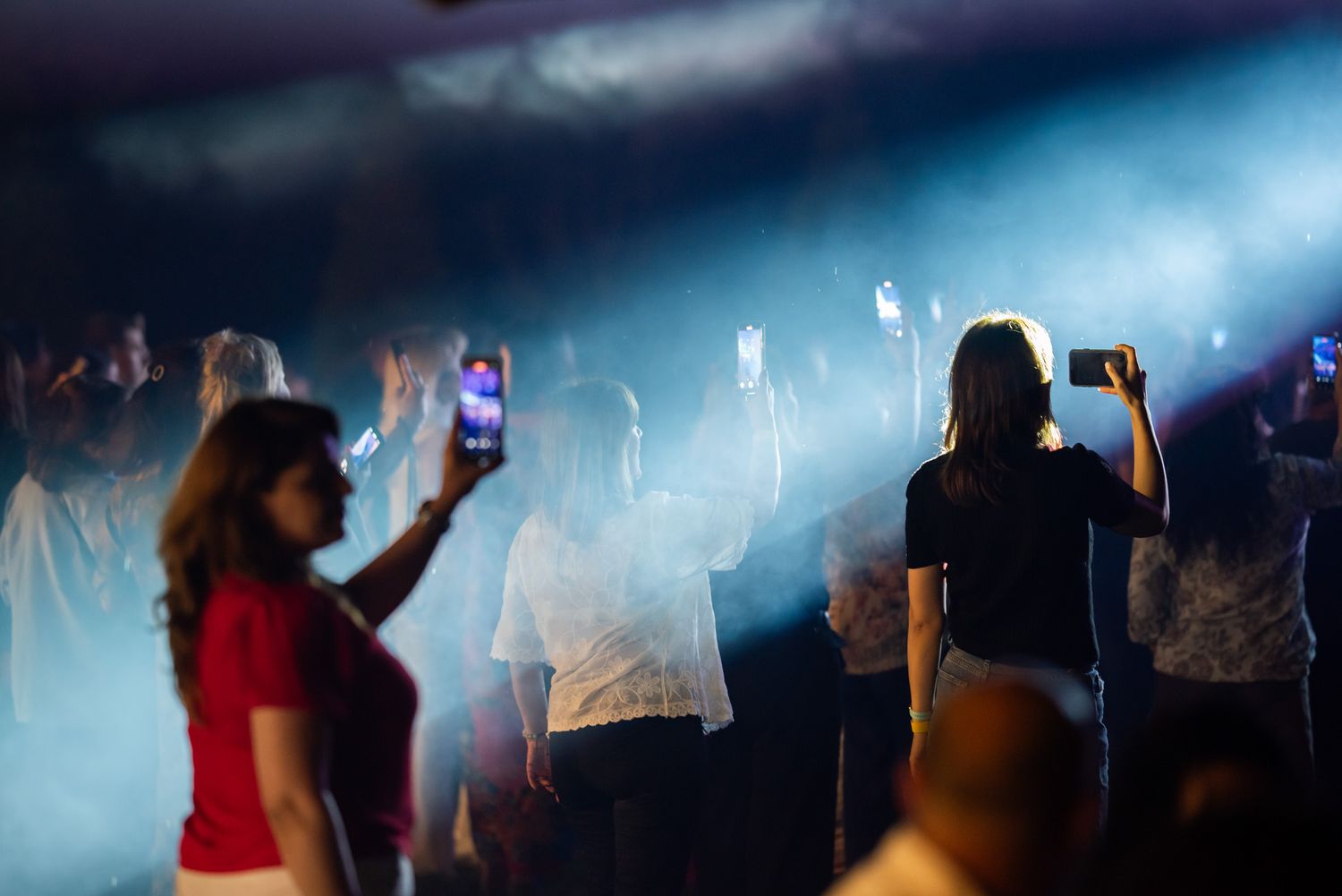 Female performers on stage entertaining a crowd with lights and smoke effects at a live show.