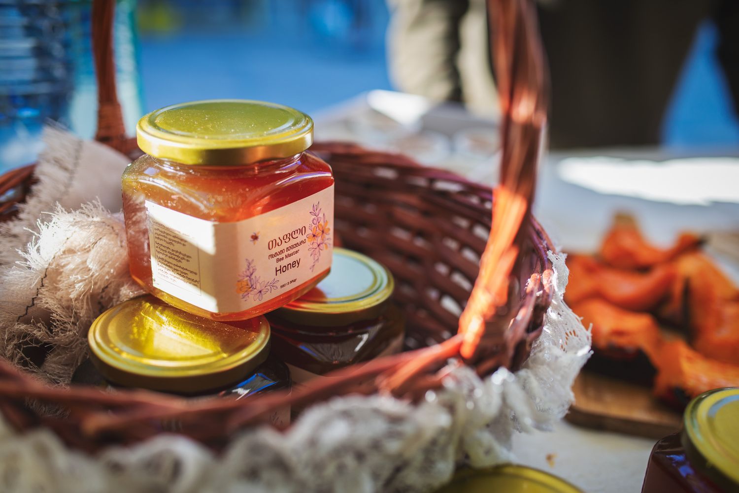 Local honey jar showcased with wooden dipper and traditional snacks on the side.